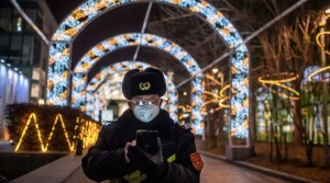 Ochranka v téměř prázdném obchodním centru v Pekingu sleduje telefon; 27. února 2020