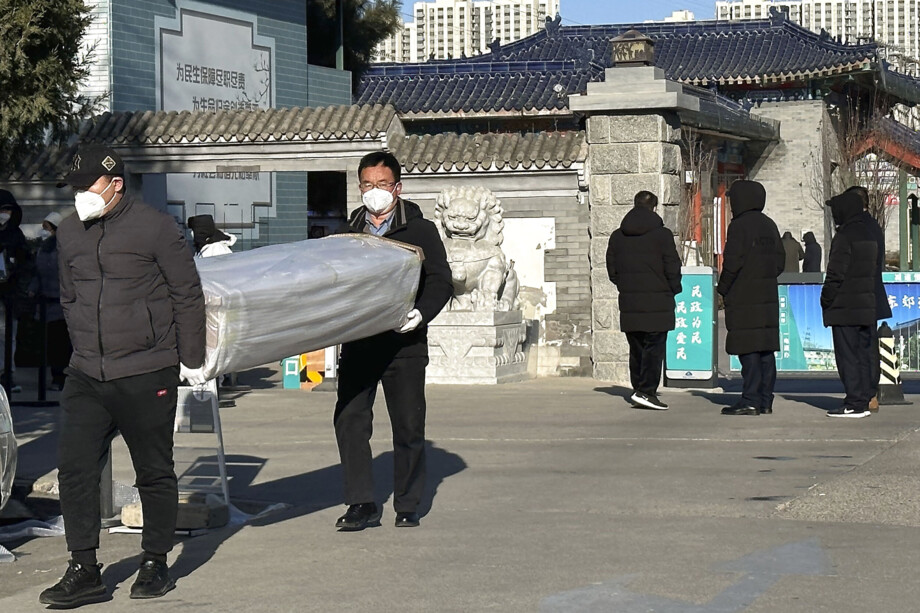 Muži vynášejí rakev z krematoria v čínském hlavním městě Pekingu. 