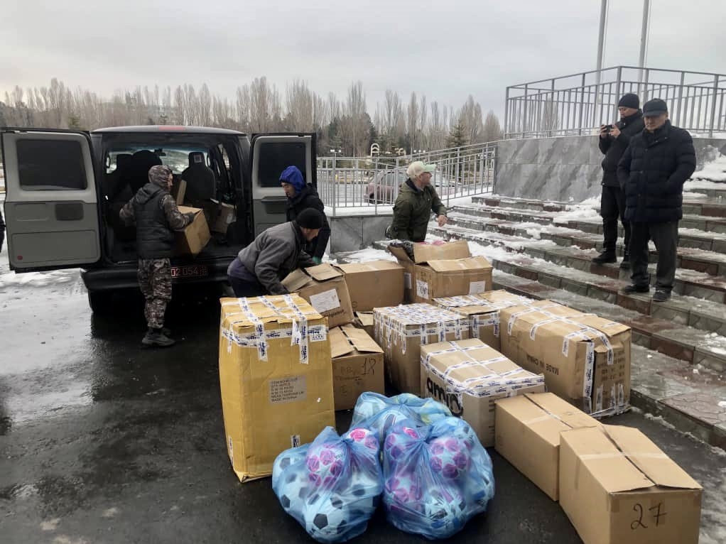 Pracovníci vykládající krabice zimního oblečení, hraček a přikrývek, které poskytla americká ambasáda pro použití navrátilci.