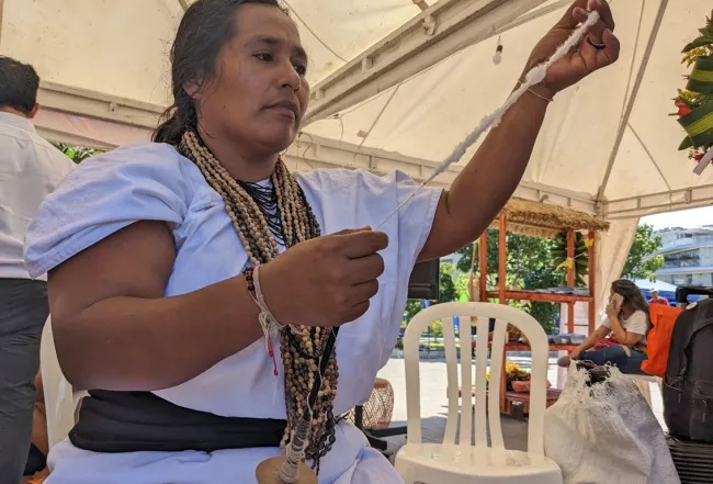 Žena z Arhuaca předvádí tradiční metodu spřádání vlny na trhu v Santa Martě.
