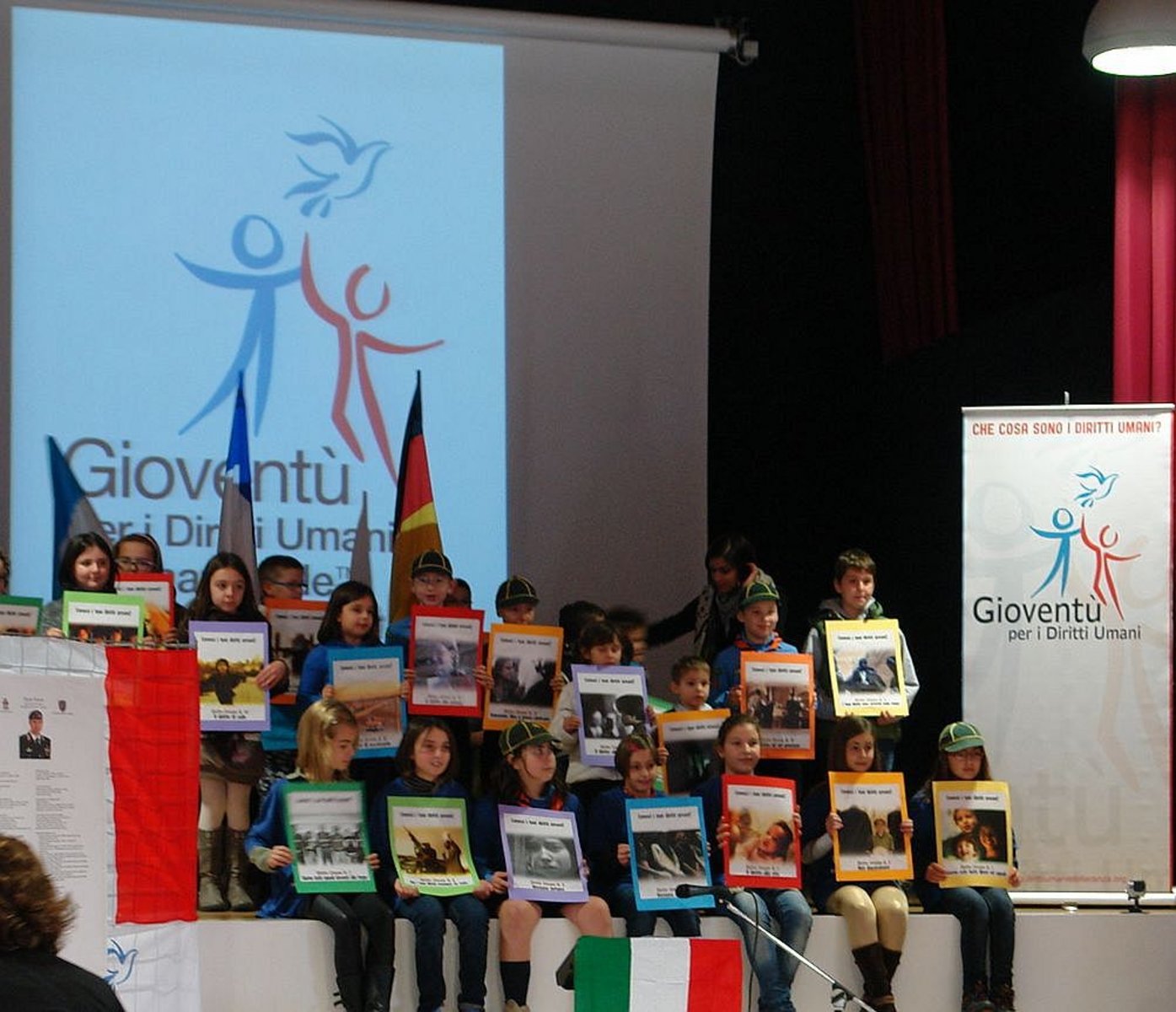 Členové padovské pobočky organizace Mládež za lidská práva v Den Mládež za lidská práva 10. listopadu 2013 na pódiu kulturního sálu sousedícího s radnicí v Grantortu